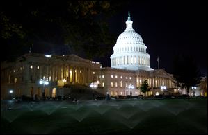Sprinklers water the lawn outside the U.S. Capitol late Saturday night in Washington.