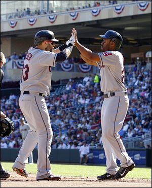 Cleveland's  Michael Bourn, right, welcomes Nick Swisher at home plate after they both scored on Swisher's home run off Twins pitcher Scott Diamond during the first inning Sunday in Minneapolis.