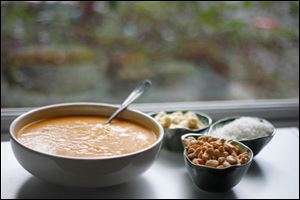 Butternut squash soup with a garnish of cashews, roasted coconut, and bananas.