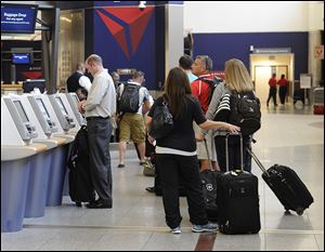 Delta Air Lines passengers line up to check luggage at Hartsfield-Jackson Atlanta International Airport in Atlanta. Delta customers now have the option to purchase an upgrade that includes a free checked bag, among other perks.