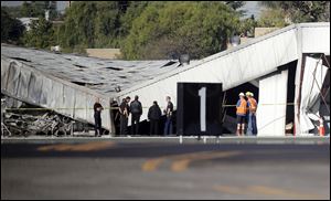Airport officials and investigators stand near a collapsed hangar at the site of a plane crash in Santa Monica, Calif. 