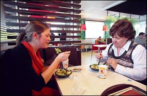 Aimie Zvosec of Chicago, left, and Dina Phillip of Naperville, Ill., dine on salads from McDonald’s dollar menu in Oak Brook, Ill.