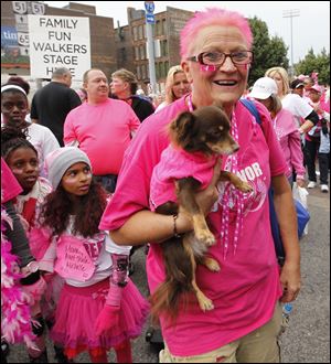 Cathie Patterson, a nine-year cancer survivor of Toledo, carries her dog Coco during the walk in Sunday's Komen Race for the Cure downtown.