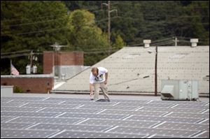 Mike Easterwood checks one of the solar panels installed on the roof of  his 1947-era building in Decatur,Ga.  Easterwood paid about $320,000 to install nearly 400 solar panels on top of his self-storage business near Atlanta. 