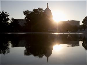 The sun rises behind the Capitol in Washington, today as the political stare-down on Capitol Hill shows no signs of easing