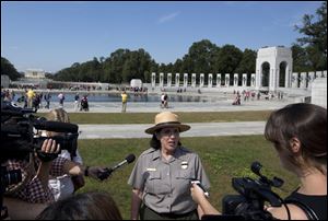 National Park Service spokeswoman Carol Johnson speaks to reporters at the National World War II Memorial in Washington, Tuesday as a group of veterans walked past barriers at the closed World War II memorial with help from members of Congress. 