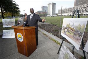 Toledo Mayor Mike Bell talks about talks about the Promenade Park Phase II construction project. Artist's renderings of later phases are on easels surrounding the mayor.
