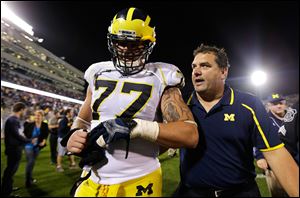Michigan head coach Brady Hoke, right, talks with offensive linesman Taylor Lewan (77) after a win against Connecticut.