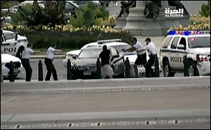This image from video provided by Alhurra Television shows police with guns drawn surrounding a black Infiniti near the U.S. Capitol in Washington. A woman with a young child inside tried to ram through a White House barricade, then led police on a chase toward the Capitol, where police shot and killed her, witnesses and officials said. 