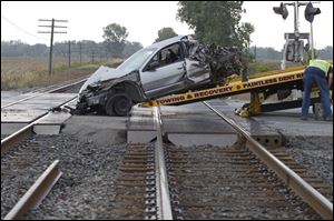 Workers from Reinhart Auto Body load a car onto a flatbed truck after it collided with a train at the CSX railroad tracks on U.S. 6 in Bradner, Ohio.