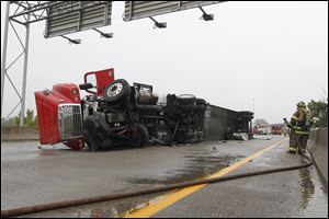 Firefighters stand by at an overturned truck on N I-75 south of Toledo.