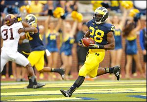 University of Michigan running back Fitzgerald Toussaint (28) scores a touchdown against University of Minnesota during the first quarter.