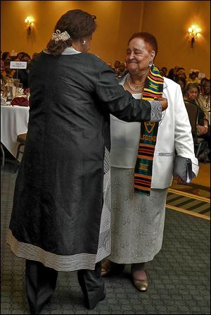 Helen Cooks places a scarf of honor around Lola Glover of the Coalition for Quality Education during the Legends Luncheon. 