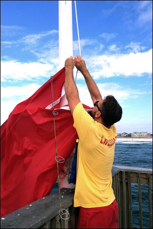 A lifeguard hangs a red flag indicating dangerous surf conditions at Pensacola Beach, Fla. 