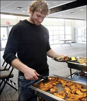 Kyle Rogers serves himself a piece of fried Walleye at a team fish fry this past winter. The 6-foot-3, 200-pound Rogers is entering his seventh pro hockey season.