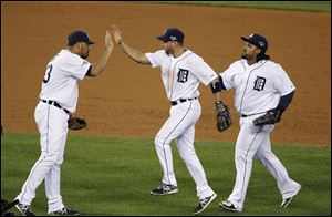 Detroit Tigers relief pitcher Joaquin Benoit, left, greets teammates Omar Infante and Prince Fielder, right, after the Tigers' 8-6 win over the against the Oakland Athletics in Game 4 of baseball's American League division series in Detroit.