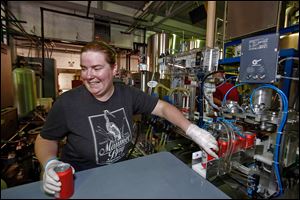 Shannon Mohr moves canned Buckeye Beer to be pasteurized at Maumee Bay Brewing Co. The brewery started bottling some of its craft beers earlier this year, and the portable canning line became operational at the beginning of the month.