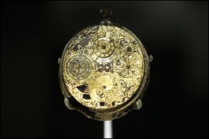A  gilt-brass and enamel clock-watch with alarm and calendar made by Gaultier Ferlite is seen on display.