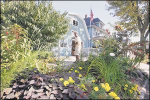 David Johnson maintains a garden at the corner of his business. At left are peach trees.