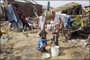 An Indian child washes utensils after eating free food distributed in the village of Podampeta on the Bay of Bengal coast in India. Podampeta was among the villages hit when Cyclone Phailin roared in over the weekend.