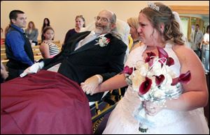 Scott Nagy hand-in-hand with his daughter Sarah is wheeled down the aisle as he gives his daughter away in marriage to Angelo Salvatore on Saturday at First Lutheran Church in Strongsville, Ohio.