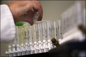 A laboratory technician prepares samples of urine for doping tests on opening day of the London Olympics.