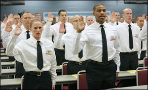 Nicole Crissman, left, and William Clark take their oath as Toledo’s largest police class since 1983 gets under way. The 61st Toledo Police Department Basic Police Officer Academy began Tuesday at the Toledo Police Academy on the Owens Community College campus in Perrysburg Township. 