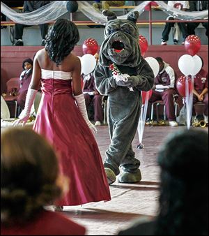 Brittani Graves of the Class of 2017 is met by her escort, the Bulldog mascot, during the kickoff of Scott High’s centennial celebration in the school’s field house Friday.