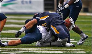 Navy's Cody Peterson yanks back the head of UT's David Fluellen during 2nd half at the University of Toledo Glass Bowl in Toledo, Ohio. Fluellen was taken out of the game injured. No penalty called.