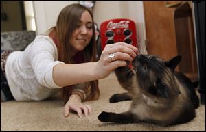 Danielle Wiley gives a treat to her cat Cairo in Ballville Township, Ohio. One of her three cats loves to swallow anything stringlike.