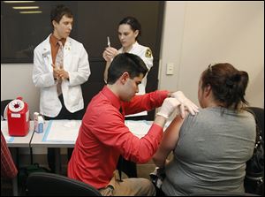Adam McCabe, a student in the University of Toledo School of Pharmacy, ad-ministers a flu shot to an uninsured woman.