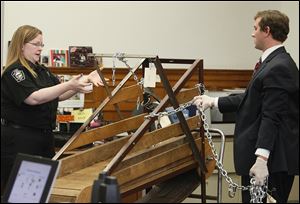 Julie Lyle, Lucas County dog warden, left, explains  how a dog’s collar is connected to the dog tread-mill as Charles McDonald, an assistant Lucas County prosecutor, listens during a bench trial on Monday in Lucas County Common Pleas Court. Carl Steward is facing six counts of dog fighting.