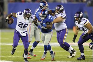 Minnesota Vikings running back Adrian Peterson (28) breaks a tackle by New York Giants' Jon Beason (52) as Jerome Felton (42) trails the play during the second half.