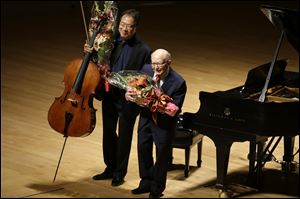 Cellist Yo-Yo Ma, left, and Holocaust survivor George Horner, right, hold flowers as they bow after performing together on stage at Symphony Hall Tuesday, Oct. 22, 2013, in Boston. 