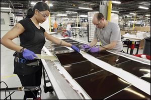 Employees work on solar panels at the Xunlight Corp. plant.  A Xunlight official says the company ‘got ahead of itself.’