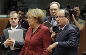 German Chancellor Angela Merkel, second left, and French President Francois Hollande, second right, arrive for a round table meeting at an EU summit today in Brussels.