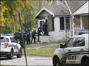 Toledo police rush a Montrose Avenue home where they were alerted by K-9 unit to the presence of a suspect in an armed robbery. Police released a stun grenade prior to entering on Friday.