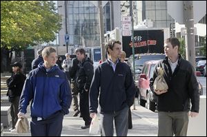 Corey Trucker, left, Matt Hinkle, center, and Jayme Ranker talk on their way back to work after picking up lunch from a food truck parked in downtown Toledo. Food trucks are growing in popularity across the United States.