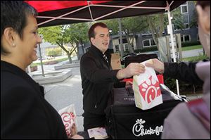 Liz Simon, left, jokes with Brandon Hirn, an assistant manager at Chick-fil-A, center, while he serves another customer during lunchtime. Several food trucks have set up near the corner of Madison and St. Clair streets on Tuesdays and Thursdays from 11 a.m. to 1:30 p.m.