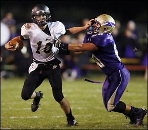 Perrysburg QB Gus Dimmerling, left, tries to run past Maumee’s Dakota Yeary. Dimmerling ran for 216 yards and threw for 260.