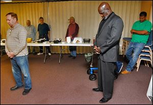 Mayor Mike Bell prays with church members at a men's prayer breakfast at Westside Church in Toledo.