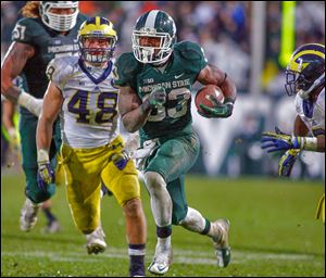 Michigan State's Jeremy Langford runs between Michigan's Desmond Morgan, left, and Raymon Taylor for a 40-yard fourth-quarter touchdown.
