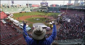 Carlos Arredondo raises his arms as he waves to fans at Fenway Park in advance of the Boston Red Sox's championship parade today in celebration of the baseball team's World Series win.
