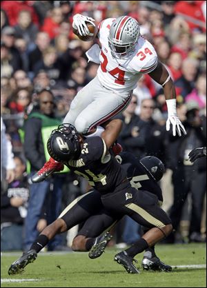 Ohio State running back Carlos Hyde leaps over Purdue defensive back Frankie Williams, left, and safety Taylor Richards during the first half Saturday in West Lafayette, Ind.