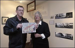 John Huss and Lisa Swickard, at a coffee house in Tiffin, hold a rendition of the cover of their book on the razing of the Seneca County Courthouse. 