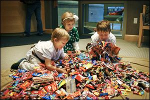 Logan Schmakel, 5, left, plays with a large pile of candy with his siblings Madison, 6, and Brandon, 10,