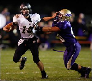 Perrysburg QB Gus Dimmerling (10) runs the ball against  Maumee's Dakota Yeary (60) during a football game last Friday.