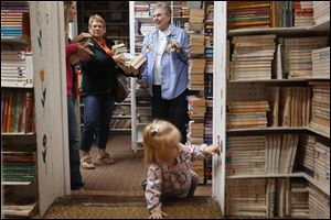 Brooklyn, 1, explores Munchkin Book Store as her mother Jacki Moyer, left, and grandmother, Marlene Baer, both of Archbold, Ohio, center, talk with Barbara Kerschner, right.