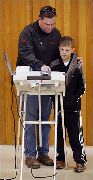 Rob Marquette shows his son Dominic, 10, how to vote at St. Paul's Episcopal Church in Oregon.