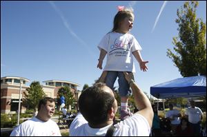 As Tyler Wiley, of Toledo, left, watches Tim Szparka, of Sylvania, center, holds his daughter Lindsey, 4, aloft while joking around during the annual Buddy Walk.